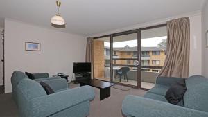a living room with two blue chairs and a large window at Berdella Park 9 in Port Macquarie