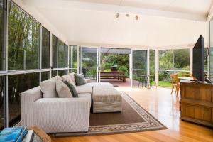 sala de estar con sofá blanco y ventanas grandes en Maldas Retreat Pet Friendly Absolute Beachfront with Spa en Culburra Beach