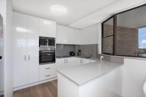 une cuisine blanche avec des placards blancs et une fenêtre dans l'établissement Tasman 15, à Port Macquarie