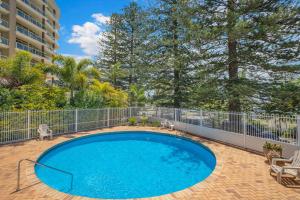 - une piscine sur une terrasse avec une clôture et des arbres dans l'établissement Tasman 15, à Port Macquarie