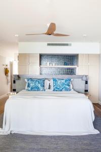 a bedroom with a large white bed with blue pillows at Beach Club in Hamilton Island