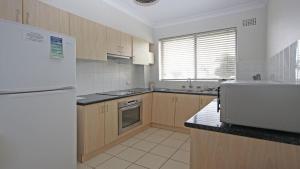 eine Küche mit Holzschränken und einem weißen Kühlschrank in der Unterkunft Flynns View 8 in Port Macquarie