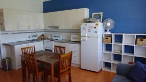 Una cocina con mesa y sillas y un refrigerador. en Forster Lodge 10, en Forster