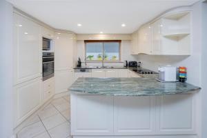 - une cuisine avec des placards blancs et un comptoir en marbre dans l'établissement 22 The Promenade, à Port Macquarie
