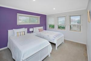 Dormitorio púrpura con 2 camas y ventanas en 22 The Promenade, en Port Macquarie