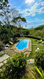 ein Schwimmbad in der Mitte eines Gartens in der Unterkunft Hotel Cerro Lodge in Tarcoles