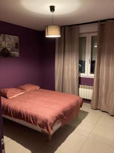 - une chambre avec un lit et un mur violet dans l'établissement Superbe appartement parking gratuit 2, à Aulnay-sous-Bois