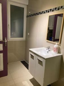 La salle de bains est pourvue d'un lavabo blanc et d'un miroir. dans l'établissement Superbe appartement parking gratuit 2, à Aulnay-sous-Bois