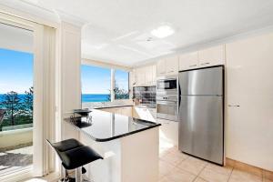 a kitchen with a refrigerator and a counter with a chair at Southern Cross - Hosted by Burleigh Letting in Gold Coast