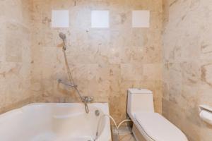 a bathroom with a white tub and a toilet at Urbanview De Ethnic Hotel Bandung by RedDoorz in Bandung +44 photos