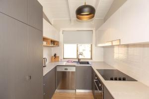 eine Küche mit weißen Arbeitsflächen, einem Waschbecken und einem Fenster in der Unterkunft Eliza Lee 2 50 Gippsland Street in Jindabyne