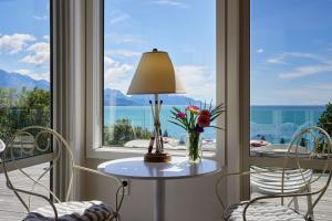 a table with flowers and a lamp in front of a window at Expansive Views, Spacious, Large Yard - KK24113 in Kaikoura