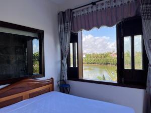 1 dormitorio con 2 ventanas y vistas al río en Lakeside Homestay, en Hoi An