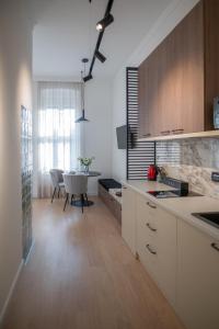eine Küche mit weißen Schränken und einem Tisch darin in der Unterkunft Deluxe Dunavska Apartment 3 in Novi Sad