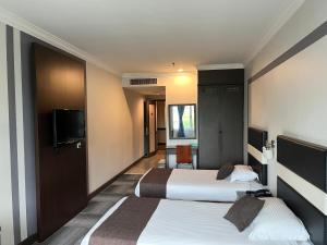 a hotel room with two beds and a flat screen tv at Legend Inn Taiping in Taiping
