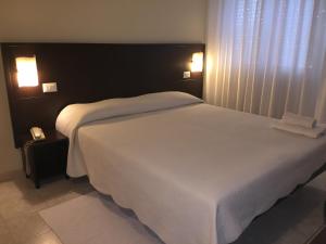 a bedroom with a large white bed with two lights at Hotel Okinawa in Rimini