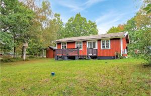 a red house in a field with a yard at Lovely Home In Rke With Wifi in Röke