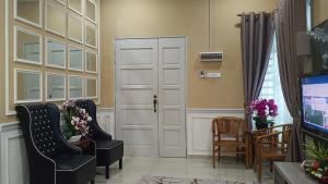 ein Wohnzimmer mit 2 Stühlen und einer Tür in der Unterkunft illa Bella Homestay Jasin in Jasin