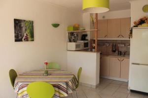 a kitchen and a table with green chairs in a room at Le Capitole in Narbonne-Plage