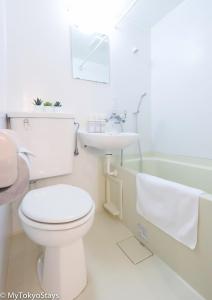 a white bathroom with a toilet and a sink at NEW! Time Square Shibuya Modern Unit. Prime Location in Tokyo