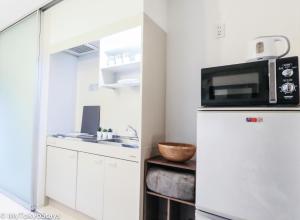 a kitchen with a microwave on top of a refrigerator at NEW! Time Square Shibuya Modern Unit. Prime Location in Tokyo