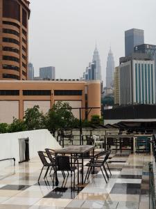 a table and chairs on a roof with a city skyline at Bestow Capsule Hostel in Kuala Lumpur