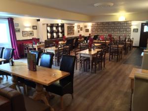 een restaurant met houten tafels en stoelen in een kamer bij Hunters Lodge Inn in Wincanton