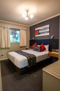 Albury Georgian Motel & Suites في البوري: غرفة نوم بسرير كبير ومخدات حمراء