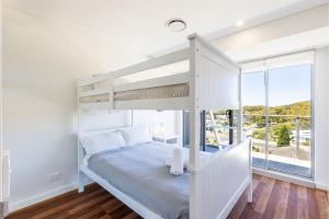 a white bedroom with a bunk bed and a window at The Shoal 503 Avra Seabreeze in Shoal Bay