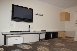 a room with a desk with a television on a wall at Edinburgh Motor Inn in Warragul