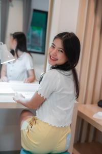 a woman is smiling in front of a bathroom sink at Tiny Krabi Hotel in Ban Khlong Chi Lat