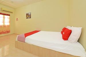 um quarto com uma cama com almofadas vermelhas e brancas em OYO 90689 Chalet Kak Siti em Kuala Terengganu