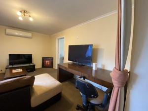 a room with a desk with a television and a chair at 4 Beds-Whole House-U2-9 Dennis Street-Reservoir in Melbourne