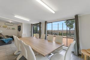 a dining room with a large wooden table and white chairs at Barefoot Waters in Tailem Bend