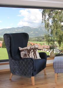 a chair in a room with a large window at Bergzauber Wohlfühlchalets in Bolsterlang