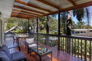 porche con sofá y mesa en la cubierta en Bella Lago - Peace and Tranquility by the Lake, en Smiths Lake