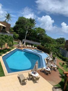 a swimming pool with chairs and umbrellas at Imbassaí Solaris Ap Beach in Imbassai