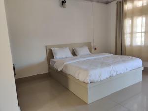 a white bedroom with a bed with white sheets and pillows at Hotel Anne Ziro in Hāpoli