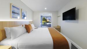 a hotel room with a large bed and a flat screen tv at Oaks Queenstown Shores Resort in Queenstown