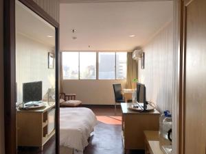新竹市にあるエルメス ホテルのベッド、デスク、コンピュータが備わるホテルルームです。