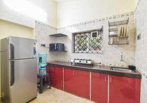 uma cozinha com armários vermelhos e um frigorífico de aço inoxidável em Garden Cottage Villa by Tropicana Stays em Lonavala