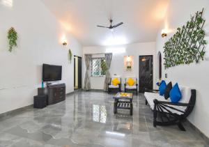a living room with a couch and a tv at Garden Cottage Villa by Tropicana Stays in Lonavala
