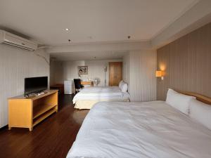 a hotel room with two beds and a flat screen tv at Hermes Hotel in Hsinchu City