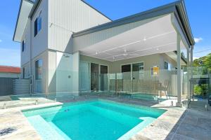 a house with a swimming pool in front of a house at Ilanga Jervis Bay-Heated Pool in Huskisson