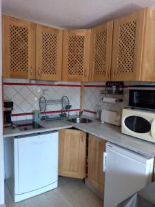 a kitchen with wooden cabinets and a white microwave at Appartement risoul, 1 pièce , 4 personnes in Risoul +1 photo