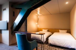 a room with two beds and a desk with a table at Mito Sannomaru Hotel in Mito