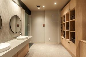 Baño con 2 lavabos y espejo en Mito Sannomaru Hotel, en Mito