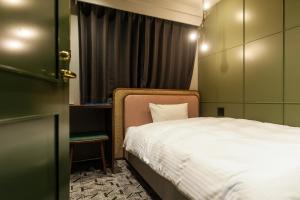 Mito Sannomaru Hotel في ميتو: غرفة نوم صغيرة بها سرير ونافذة