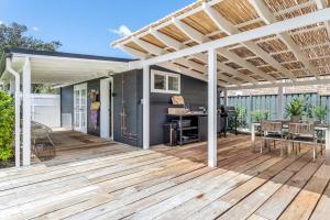 a pergola on a deck with a table and chairs at The Beach Hut in Vincentia