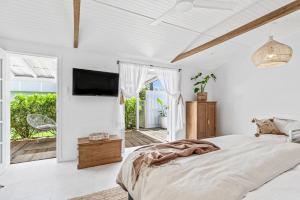 a white bedroom with a bed and a tv at The Beach Hut in Vincentia